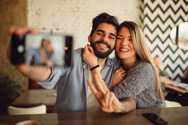 Young attractive couple making selfie with rear camera.