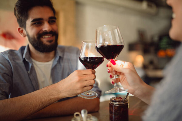 Couple clinking glasses with red wine. Couple celebrating anniversary or Valentine's day.