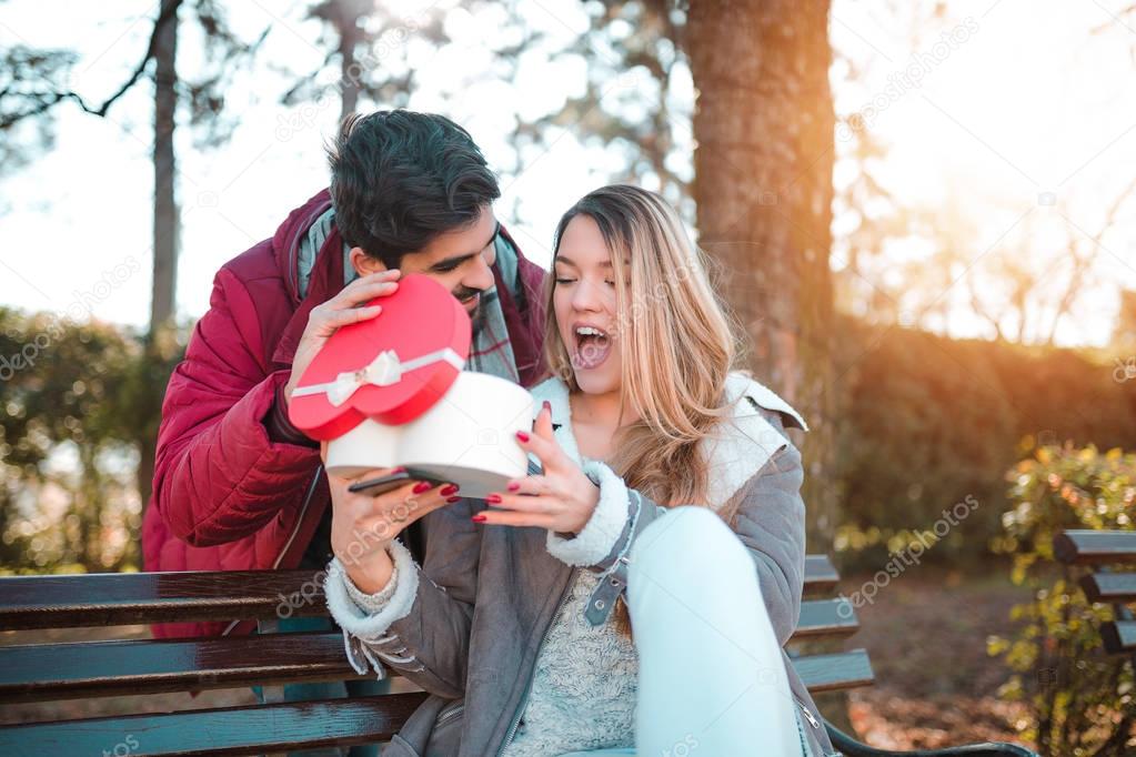 Couple in love. Man surprising his girlfriend with a gift.