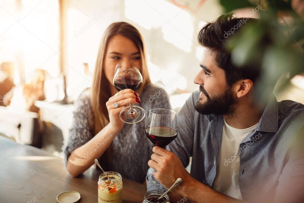 Portrait of romantic couple while drinking wine in cafe.