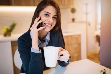 Cep telefonunuzda konuşmak ve onun evinde kahve içme mutlu iş kız portresi.