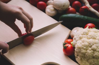 Yakın çekim kız el ile kesme kiraz domates süre güzel tırnaklar.