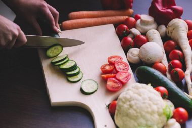 Salatalık kesme ve salata çatalı eller.