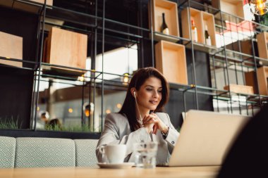 Genç işkadını kafeteryada dizüstü kullanarak portresi.