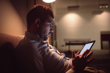 İnternet'te sörf tablet üzerinde gece genç adam.