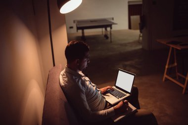 Geceleri dizüstü bilgisayar kullanan genç adam. Gece geç saatte ofiste çalışan iş adamı.