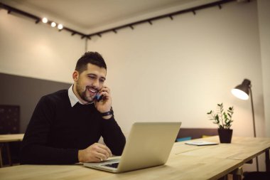 Dizüstü bilgisayar kullanma office ve cep telefonunuza konuşan işadamı.