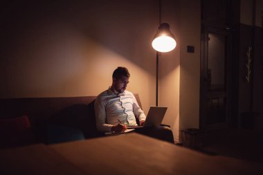 Gece geç saatlerde bilgisayar ofiste çalışan mutlu iş adamı. Yazılı notlar.