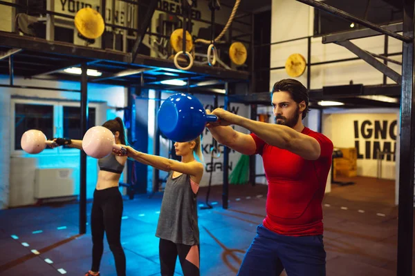 Friends doing exercises in gym. Friends lifting kettlebell.