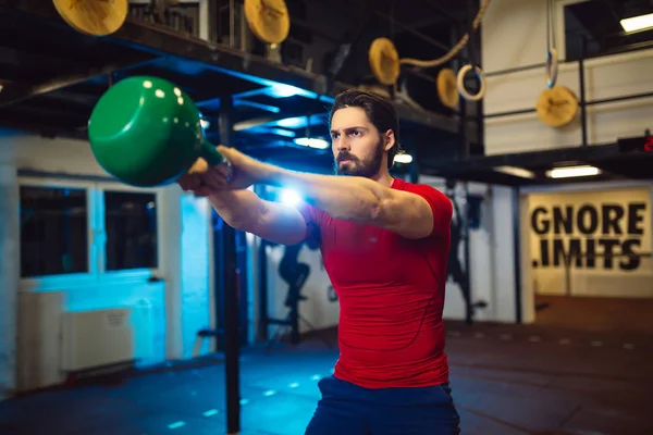 Yakışıklı adam iş ağırlık terbiye kettlebell kaldırarak.