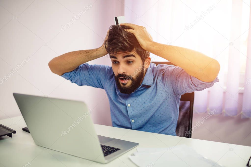 Young man surprised looking computer laptop at home or in the office