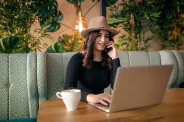 Güzel kadın güneş çatı Cafe iş molası sırasında telefonda konuşurken siyah Kazak giymiş.
