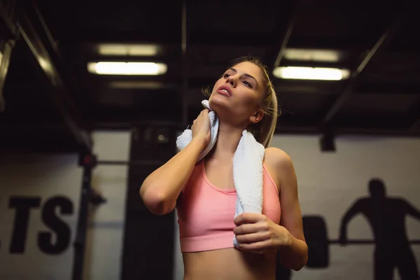 Tired girl wiping sweat with towel in gym.