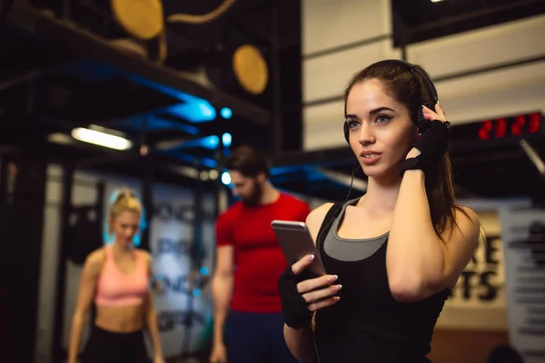 Sportswoman Smartphone Listening Music Gym Friends Talking Blurred Background — Stock Photo, Image
