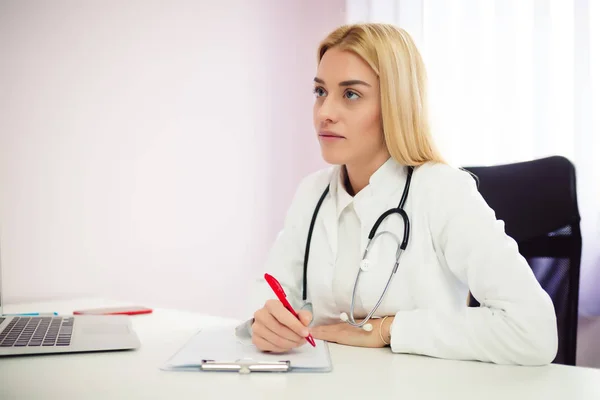 Close up of a female doctor filling up an application form while consulting patient. Medicine and health care concept