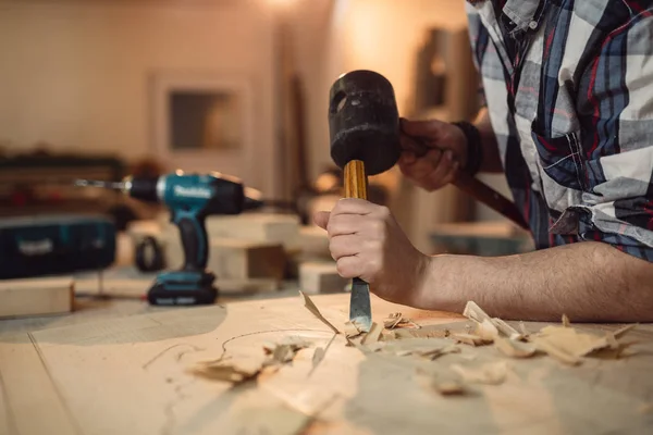 Carpenter works with chisel and hammer