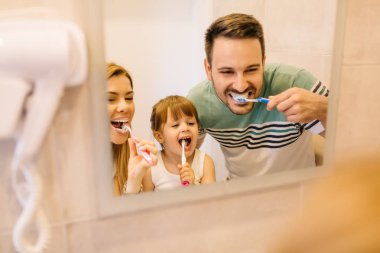 Mutlu aile banyo ayna önünde Dişlerini fırçalıyor