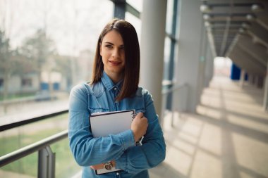 Koridorda duran onun elinde defter tutan güzel esmer kadın