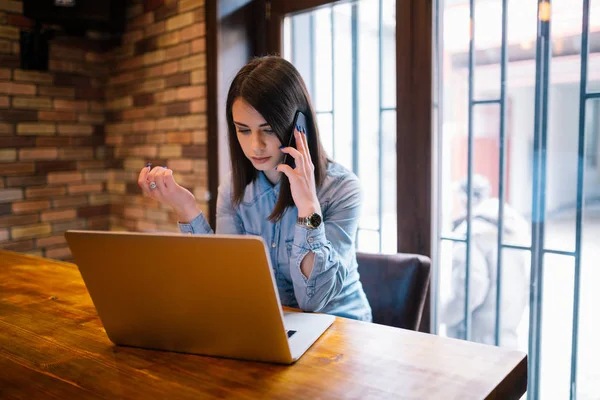 Jonge Brunette Vrouw Met Telefoongesprek Met Client Terwijl Haar Laptop — Stockfoto