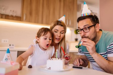 Genç kız üzerinde o aile ile doğum günü kutlamaları sırasında doğum günü pastası mumlar üfleme