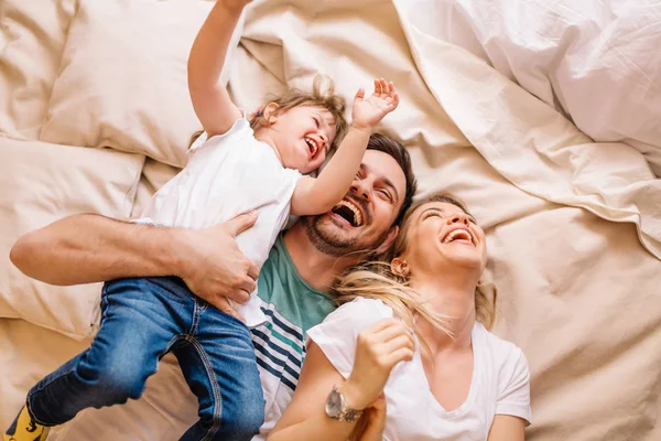 Mutlu aile yatakta yatarken ve yatak odasında eğleniyor 