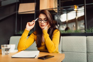 Okuma notları ve kafede otururken elinde kalem tutan güzel esmer işkadını 