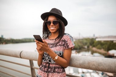 Akıllı köprü çit yanında dururken genç Afro-Amerikan kadın manifatura 