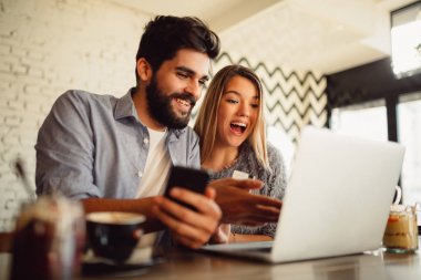 Mutlu çift dizüstü bilgisayar, akıllı telefon ve kredi kartı kullanarak alışveriş online