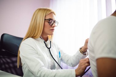 Genç Sarışın Doktor hastaya tıbbi ofis muayenede yapıyor