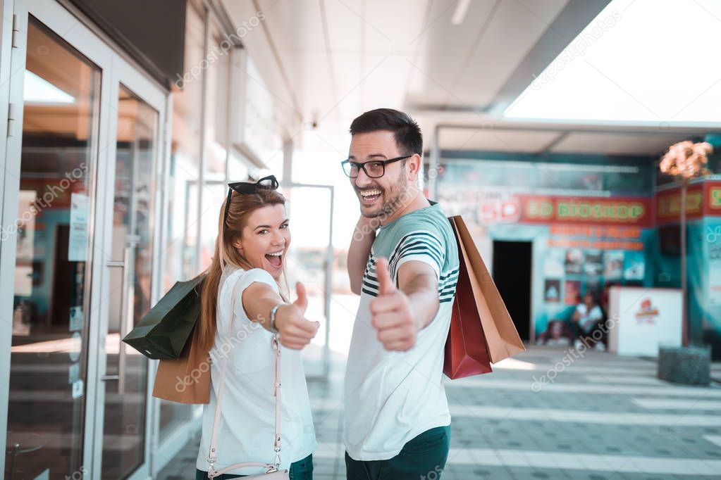 Beautiful young loving couple carrying shopping bags and enjoying together