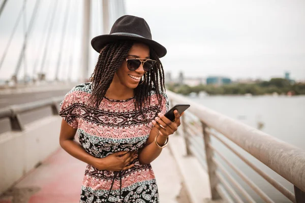 Young black woman walking in the city, next to the river, over the bridge