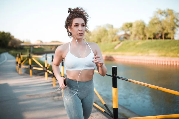妇女在一条河附近奔跑在心脏锻炼期间 — 图库照片