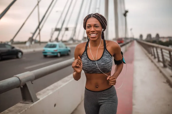 Fit african american woman running while listening to music through earphones