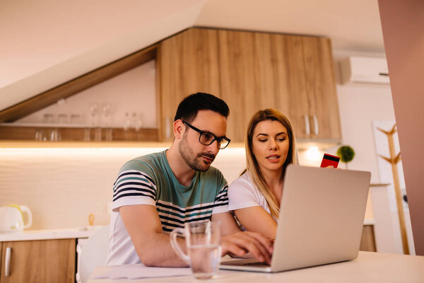 Serious young couple paying their bills online from home