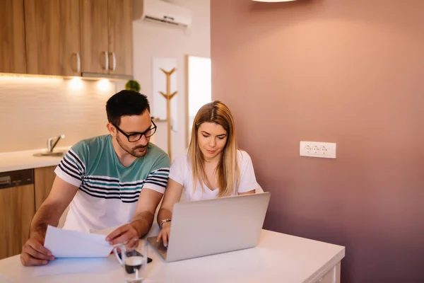 Couple working together at small office with laptop and documents