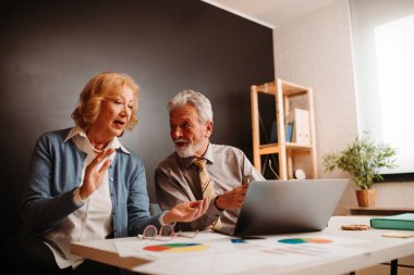 Sarışın, yaşlı kadın, ofiste otururken ortağına mevcut sorunu çözmenin bir yolunu sunuyor..