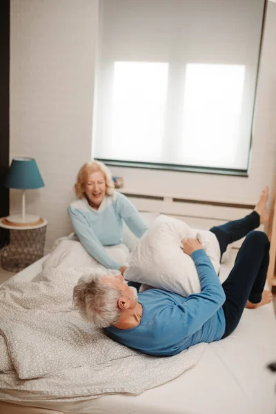 Pasangan Lansia Tertawa Bertengkar Bantal Tempat Tidur Rumah Mereka — Stok Foto