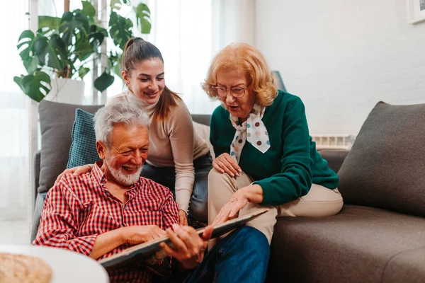 Happy family evokes memories from photo album while sitting in living room.