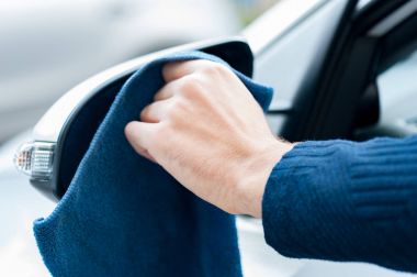 Yetişkin insan eli ile mavi mikrofiber bez ayna temizliyor. Temiz araba konsepti. Erkek handfrom pencere yan görünüm