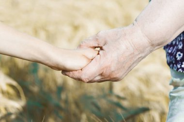 Büyükanne küçük bir kızın el bulanıklık arka plan üzerinde tutar. Kavramı güven, destek ve yardım