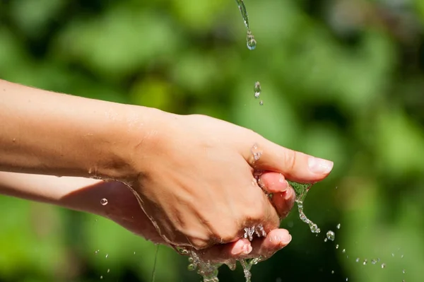 Woman washing hand outdoors. Natural drinking water in the palm. Young hands with water splash, selective focus — Stock Photo, Image