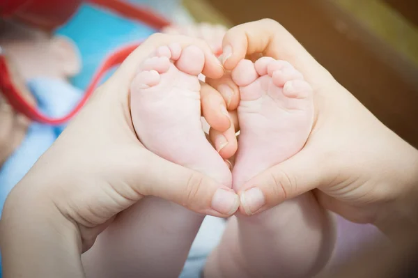 Pies de bebé en manos de madre en forma de corazón. Concepto de maternidad y cuidado . — Foto de Stock