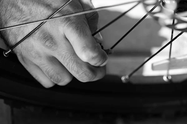 El hombre está abriendo el pezón y preparándose para el bombeo de neumáticos de bicicleta al aire libre, primer plano de las manos. Filtro blanco y negro — Foto de Stock