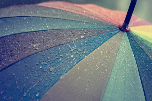 Primo piano di ombrello in colori arcobaleno nella giornata autunnale piovosa, focu sfocatura — Foto Stock