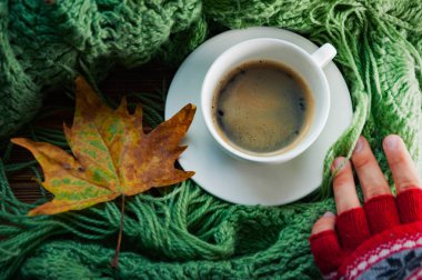 Kırmızı örgü eldiven insan elinde bir fincan sıcak kahve, en iyi görünüm, düz duruyor. Sonbahar, sıcaklığını ve konfor kavramını