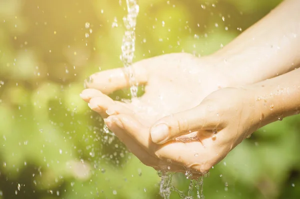 Woman washing hand outdoors. Natural drinking water in the palm. Young hands with water splash, selective focus — Stock Photo, Image