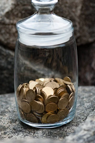 Vertikální pohled láhev peníze s mincemi v kameni. Uložení a ochraně peníze koncepce — Stock fotografie