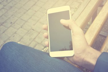  Açık havada bir akıllı telefon kullanarak adam ele. Bir kişi ile toplantı için benchand bekleyin üzerinde oturan adam. Instagra