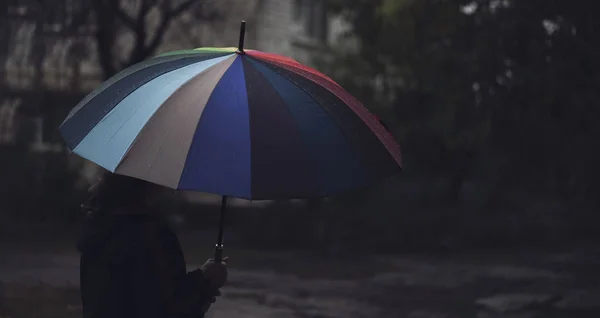 Panorama dell'uomo con ombrello colorato in piedi solitario e pensare sotto la pioggia, sfocatura fuoco. Concetto di solitudine e tristezza — Foto Stock