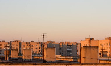 Çubuklarla günbatımında elektrik telleri için evlerin çatıları.